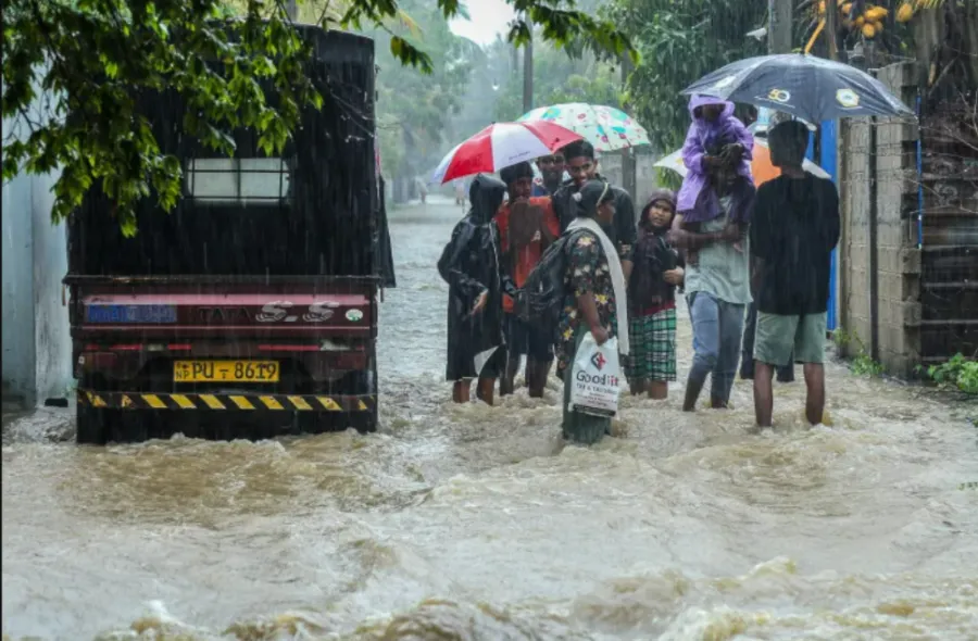 Residents wade through a flooded street during heavy rainfall in Puttalam in western Sri Lanka(Photo/AFP)